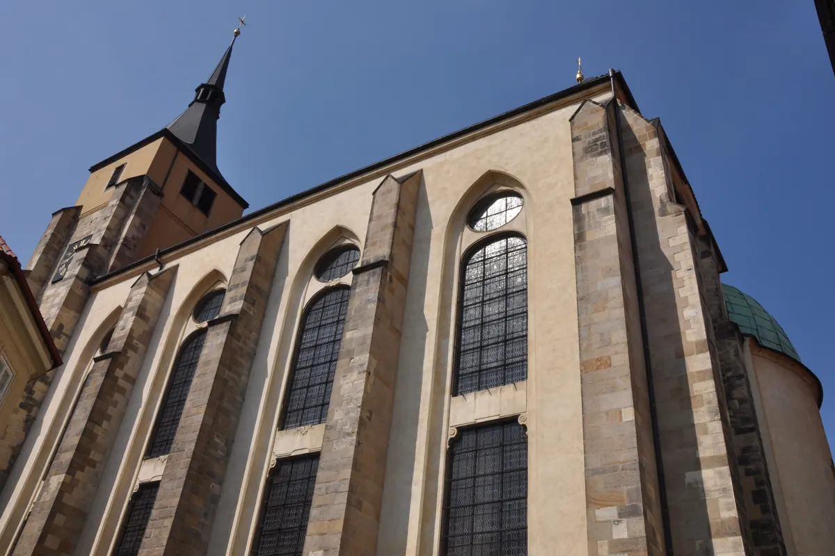 The Gothic side of St Giles' Church seen from below, with tall pointed windows between stone buttresses and a pointed tower beyond.